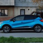 SUV compacto azul estacionado em uma rua urbana, ao lado de um edifício antigo.