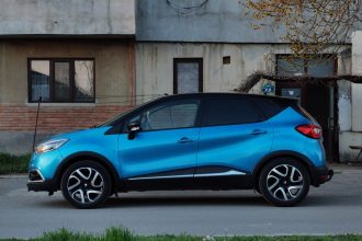SUV compacto azul estacionado em uma rua urbana, ao lado de um edifício antigo.