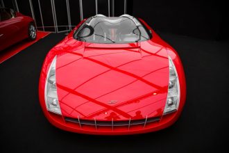Carro-conceito vermelho exposto em ambiente interno de uma mostra automotiva.