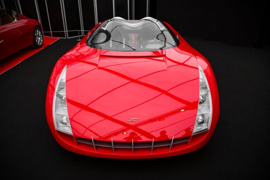 Carro-conceito vermelho exposto em ambiente interno de uma mostra automotiva.