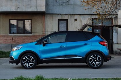 SUV compacto azul estacionado em uma rua urbana, ao lado de um edifício antigo.