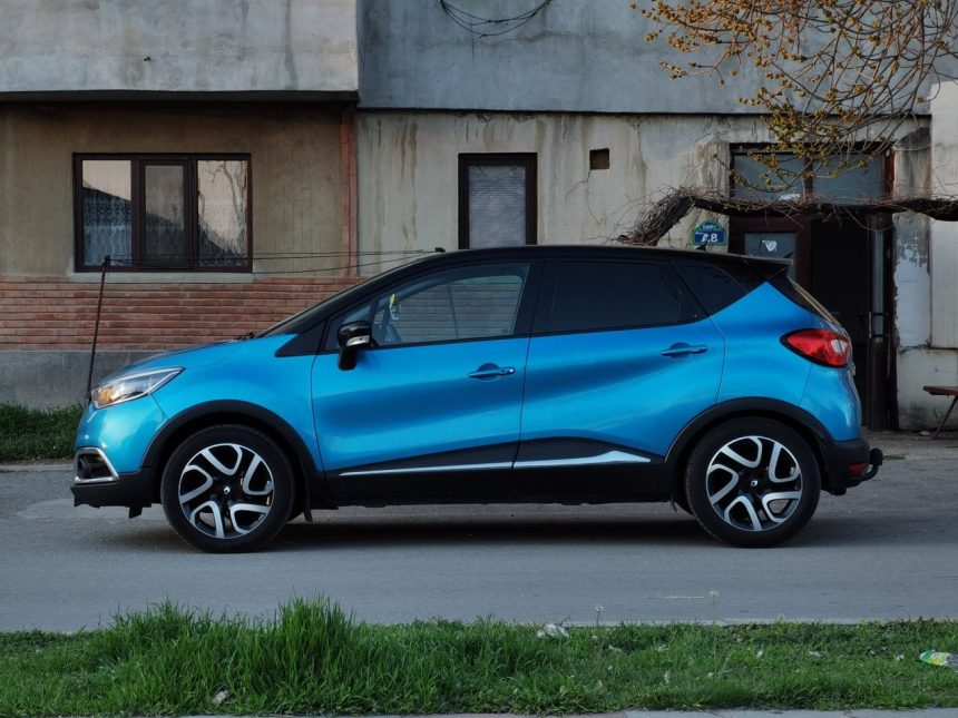 SUV compacto azul estacionado em uma rua urbana, ao lado de um edifício antigo.
